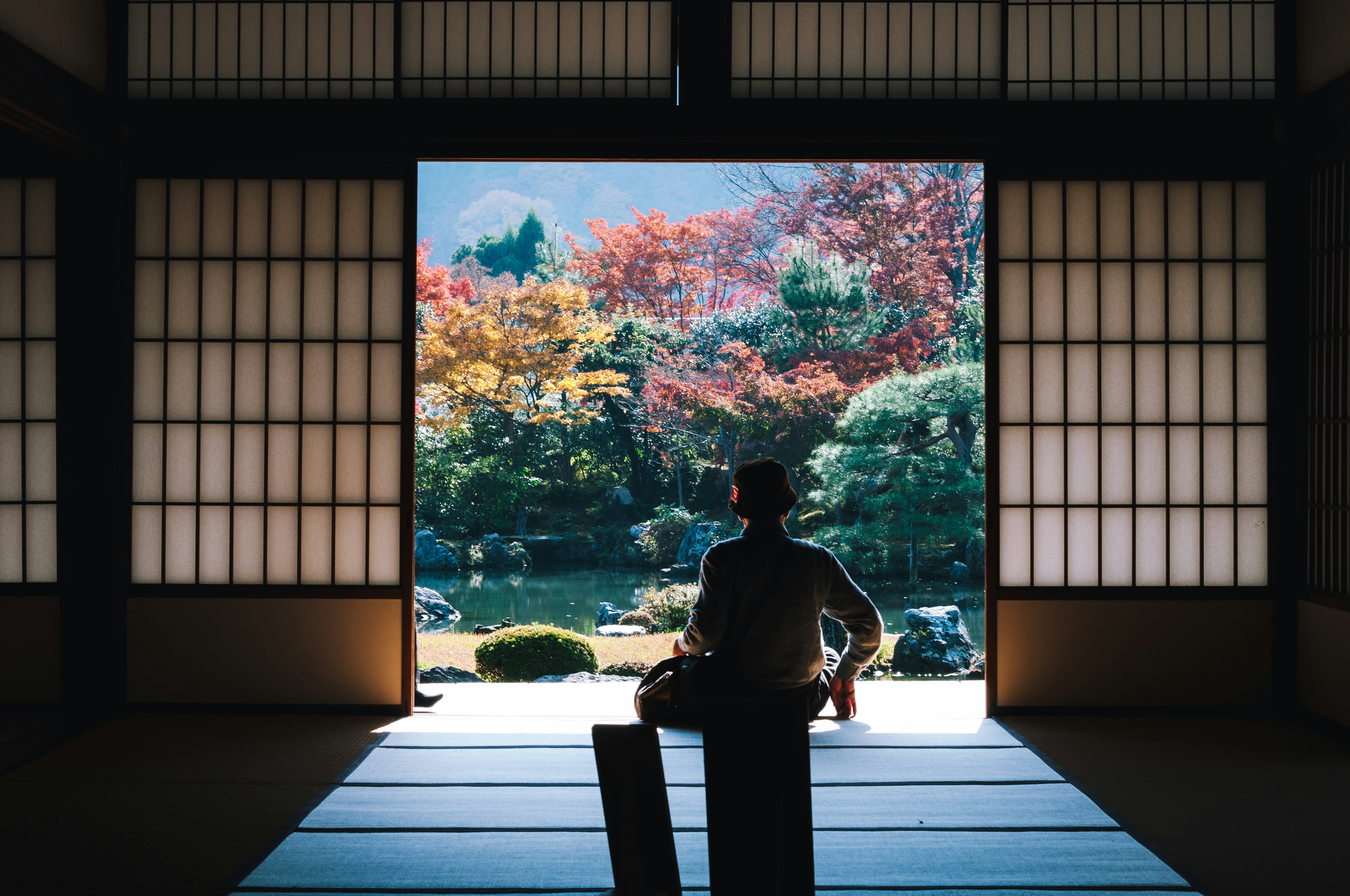 Moški sedi pred odprtimi drsnimi vrati v japonskem templju